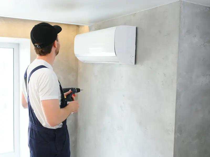 Technicien posant une unité murale de climatisation à Fréjus